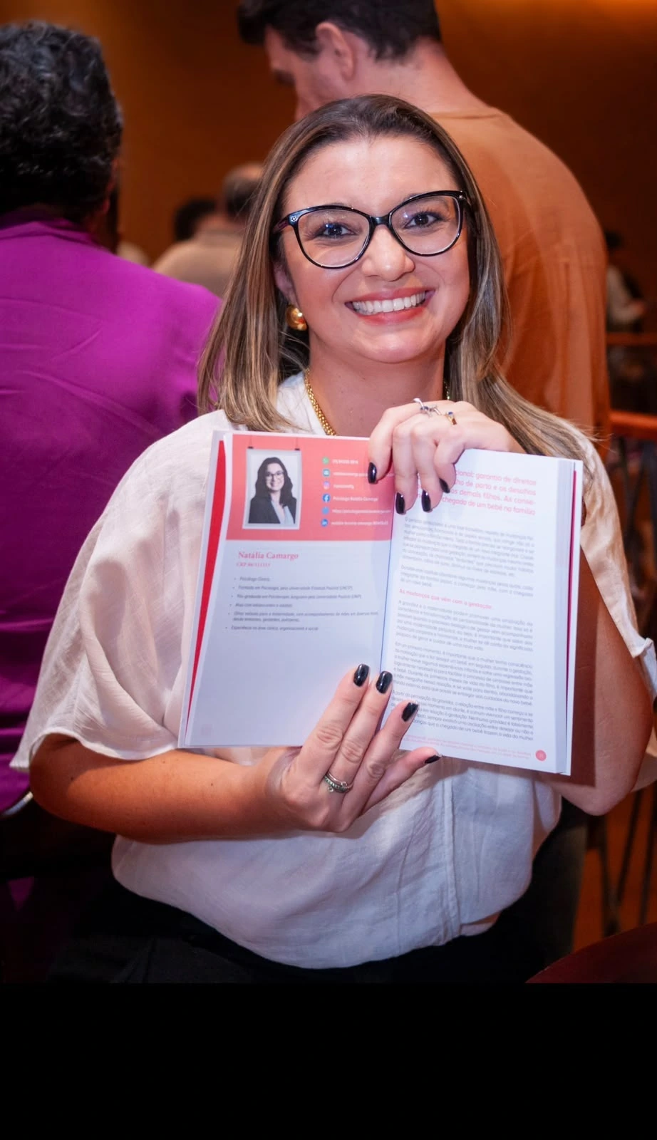 Natália Camargo segurando o livro aberto Os desafios de uma família